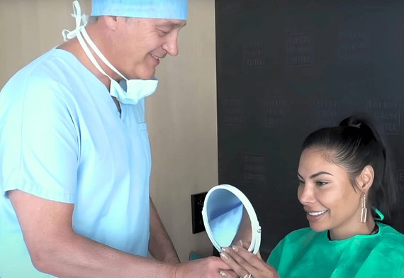 Une patiente découvre le résultat dans un miroir avec son chirurgien